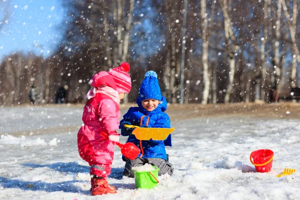 Little boy and girl digging snow in winter — Stock Photo, Image