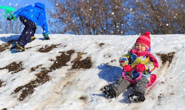 Μικρό αγόρι και κορίτσι συρόμενη σε χιόνι το χειμώνα — Φωτογραφία Αρχείου