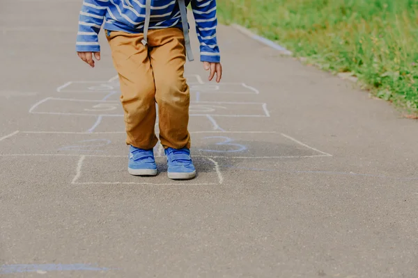 Pequeno menino jogar hopscotch no playground — Fotografia de Stock