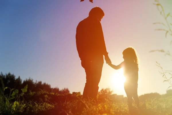 Padre e hija pequeña tomados de la mano al atardecer cielo — Foto de Stock