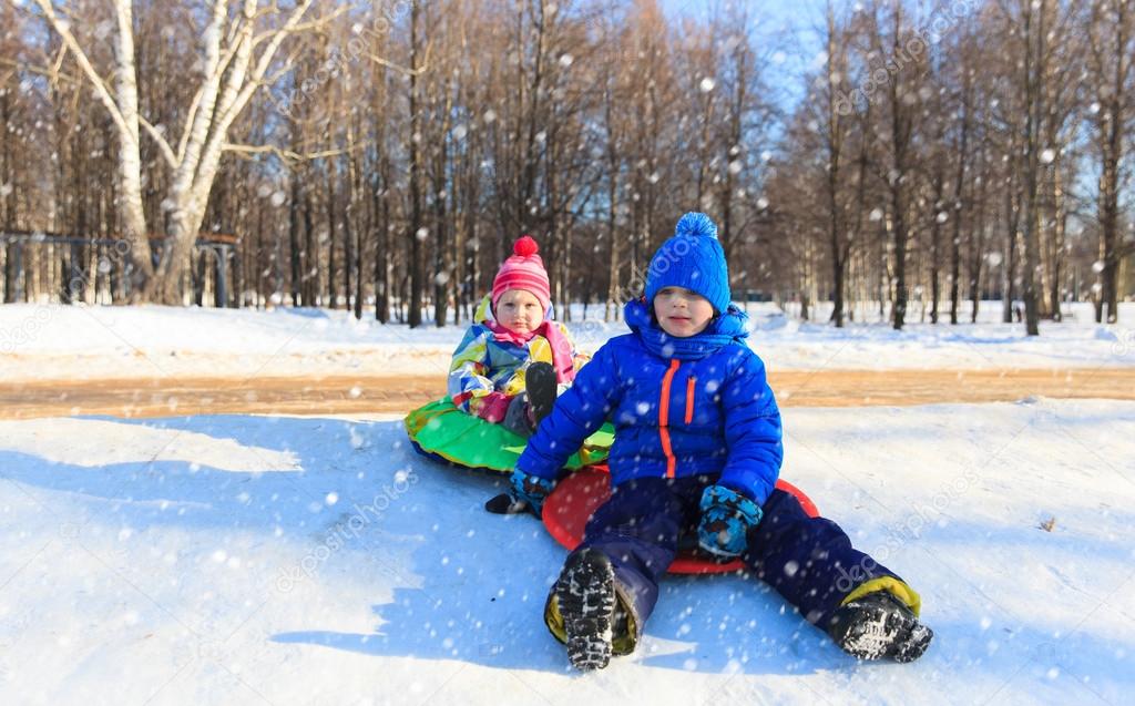 little boy and girl sliding in winter snow