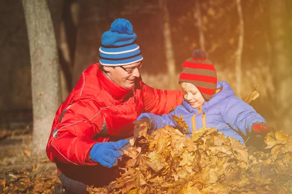 Apa és boldog kis fia játszik az őszi levelek — Stock Fotó