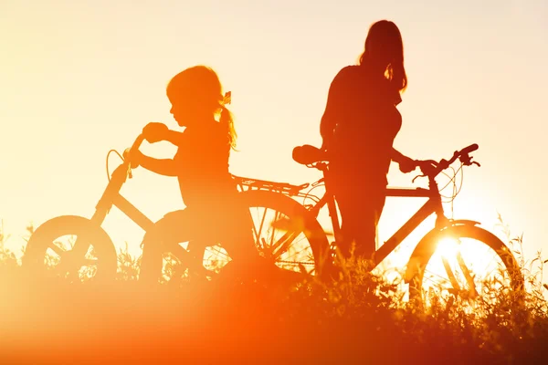 Mãe e filha andando de bicicleta ao pôr do sol — Fotografia de Stock