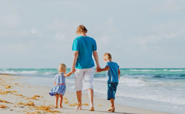 Padre y dos niños caminando en la playa — Foto de Stock
