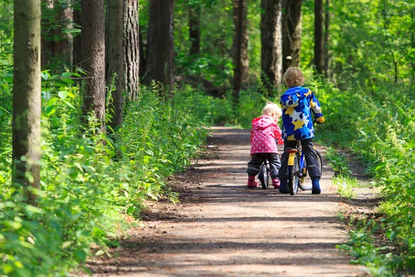 Deporte de los niños - niño y niña montar en bicicleta en el bosque — Foto de Stock