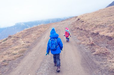 küçük erkek ve kız sırt çantaları ile dağlar giden yolda seyahat