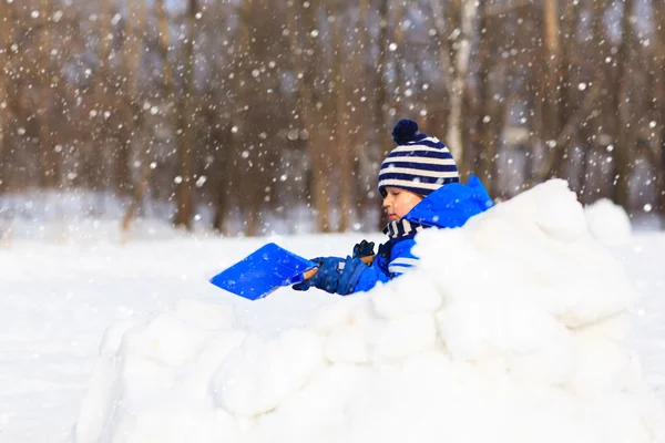 Malý chlapec kopat a hrát v zimě sněhem — Stock fotografie