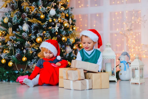 Діти відкривають різдвяні подарунки в декорованій вітальні — стокове фото