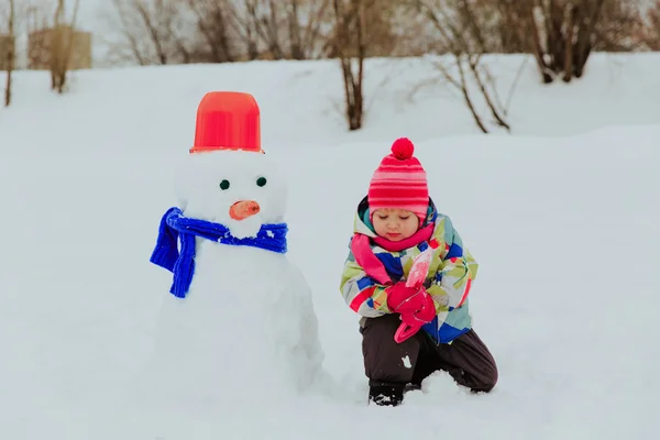 Маленька дівчинка будує сніговика в природі — стокове фото