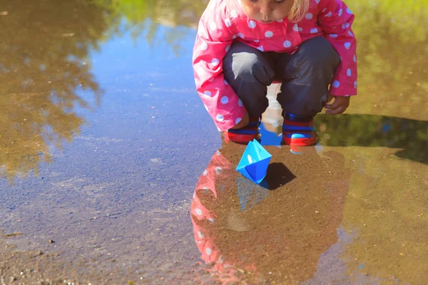 Menina brincando com barcos de papel na poça — Fotografia de Stock