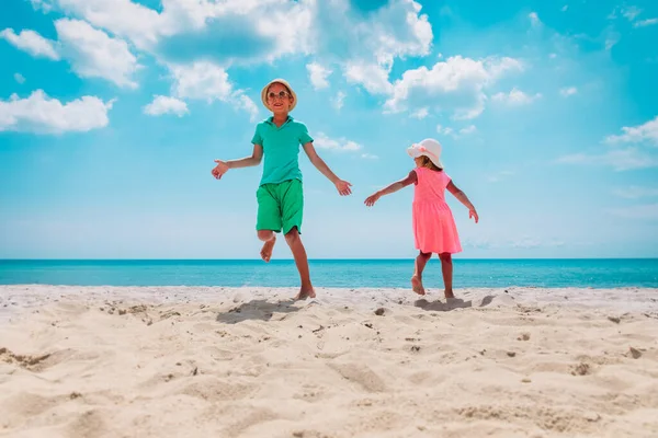 Mutlu erkek ve kız sahilde dans ediyor, çocuklar tatilin tadını çıkarıyor. — Stok fotoğraf