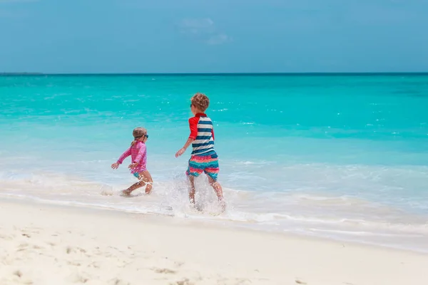 Счастливые девочка и мальчик бегут играть с волнами на пляже — стоковое фото