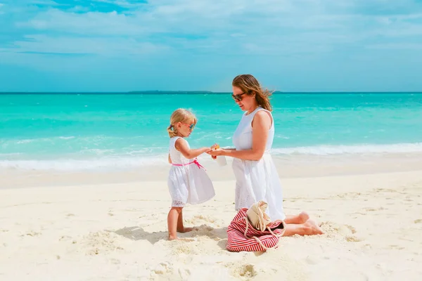 Mãe e daugghter aplicando creme protetor solar na praia — Fotografia de Stock