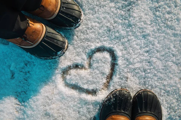 Liefde winter - voeten in sneeuwschoenen en hart in de natuur — Stockfoto