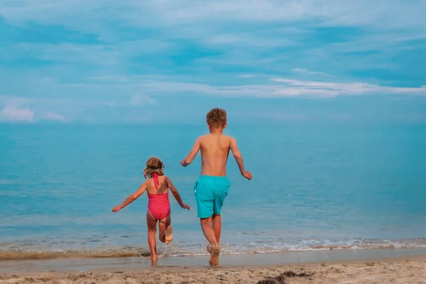 Mutlu çocuk ve kız plajda yüzer. — Stok fotoğraf