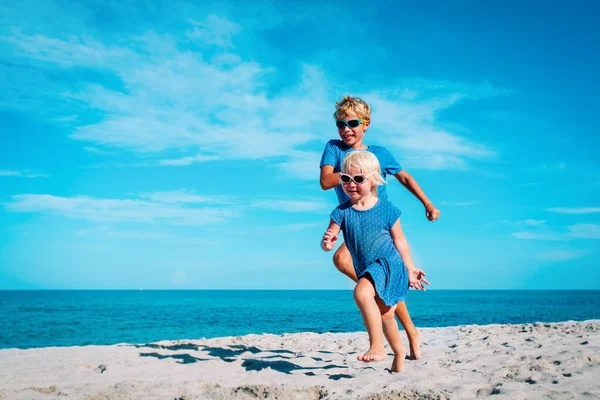Mutlu kız ve oğlan koşup kumsalda oynuyorlar. — Stok fotoğraf