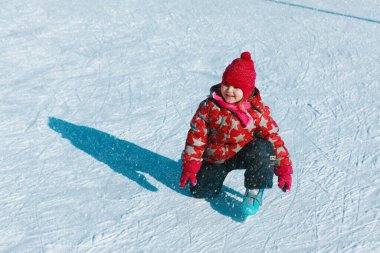 Mutlu küçük kız kışın paten kaymayı öğreniyor.