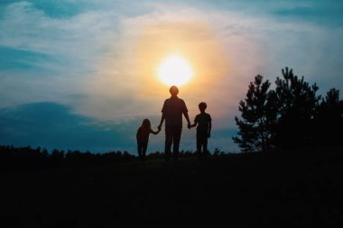 Baba oğul ve kız gün batımında yürüyün.