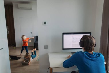 Aile evde kalır, baba bilgisayarda çalışır, çocuklar dans eder ve eğlenir.