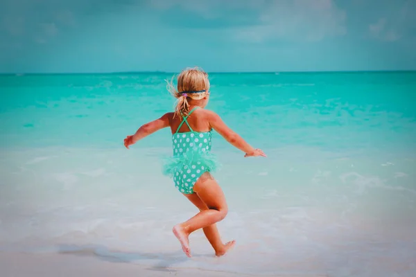 Gelukkig klein meisje rennen en spelen met water op het strand — Stockfoto