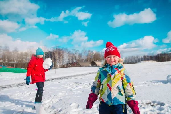 Kinder spielen im Winterschnee, Junge und Mädchen bauen Schneemann — Stockfoto