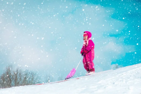 Schattig klein meisje graven winter sneeuw in de natuur — Stockfoto