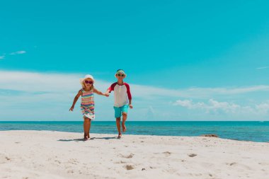 Mutlu çocuk ve kız tropik plajda koşuyorlar.