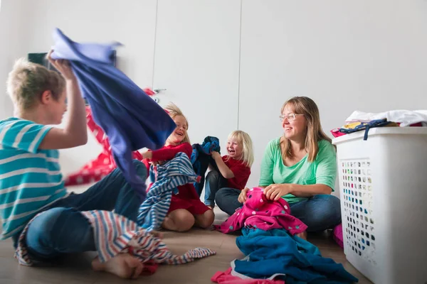 Famille faisant la lessive à la maison, mère avec des enfants s'amusent tout en triant les vêtements — Photo