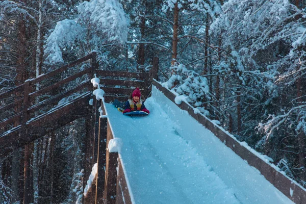 Glückliches nettes Mädchen, das auf der Schneerutsche im Winter in der Natur rutscht — Stockfoto