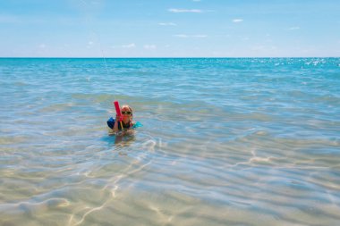 Mutlu tatlı kız sahilde su tabancasıyla oynuyor.