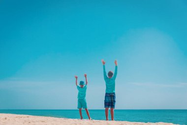 Mutlu baba ve oğul kumsalda el ele tutuşun.