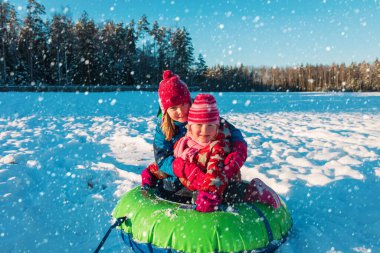 Mutlu küçük kızlar kış karında kayar, çocuklar dışarıda eğlenir.