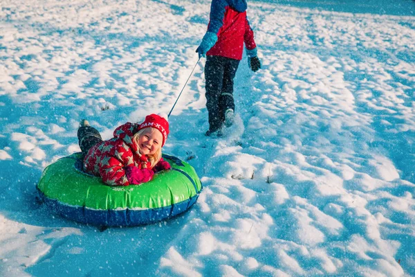 Roztomilý holčička skluzavka v zimě sníh, rodina se baví venku — Stock fotografie