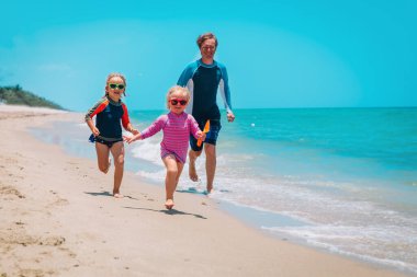 Mutlu aile koşuları ve kumsal tatilleri, baba ve küçük kız eğlenin