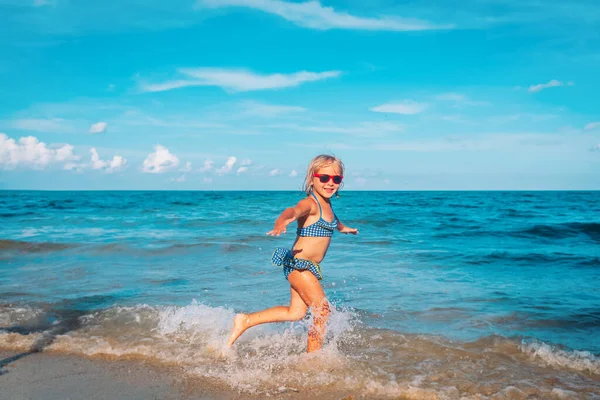 Счастливая милая девушка бегает и играет с волнами на пляже — стоковое фото