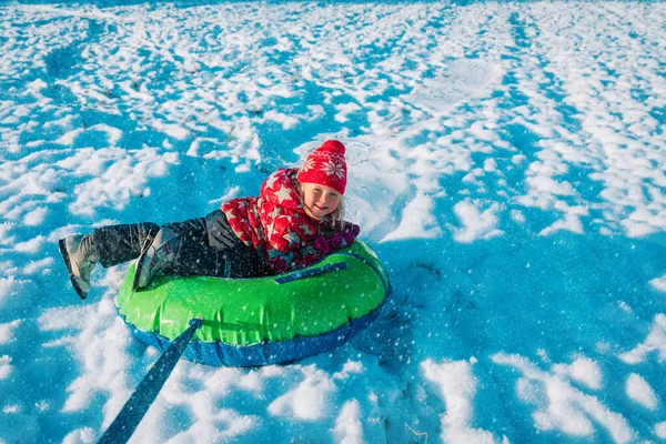 Happy cute little girl slide in the winter in a tube — Stock Photo, Image