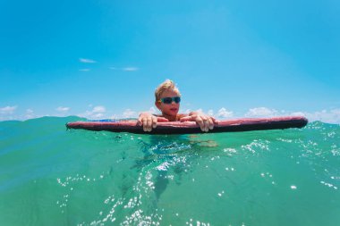 Sörf tahtasında mutlu bir çocuk, aile tatili.