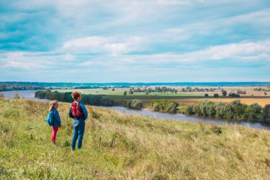 Çocuklar doğada seyahat eder, kız ve erkek manzaranın tadını çıkarırlar.