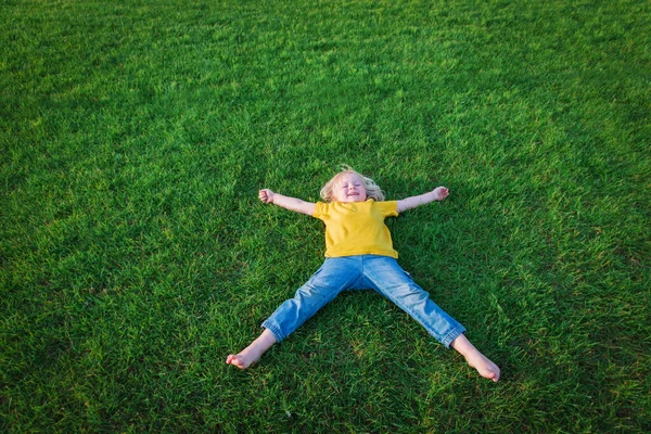 Schattig gelukkig meisje ontspannen liggend op groen gras in de zomer Stockfoto