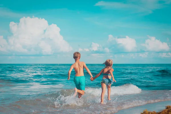 Bambina e ragazzo correre e giocare con l'acqua in spiaggia — Foto Stock