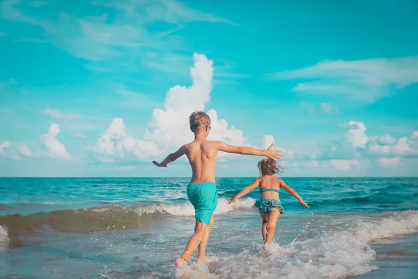 Bambina e ragazzo correre e giocare con l'acqua in spiaggia — Foto Stock