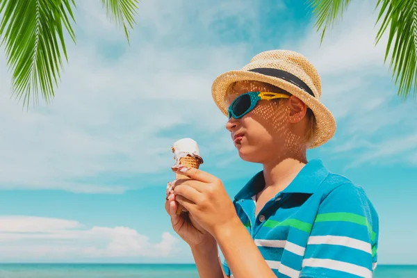 Gelukkig schattig jongen eten ijs op het strand Stockfoto