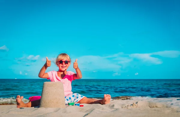 Schattig gelukkig meisje spelen met zand op het strand Stockafbeelding