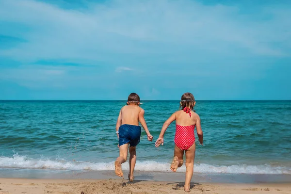 Дети бегут плавать на тропический пляж — стоковое фото