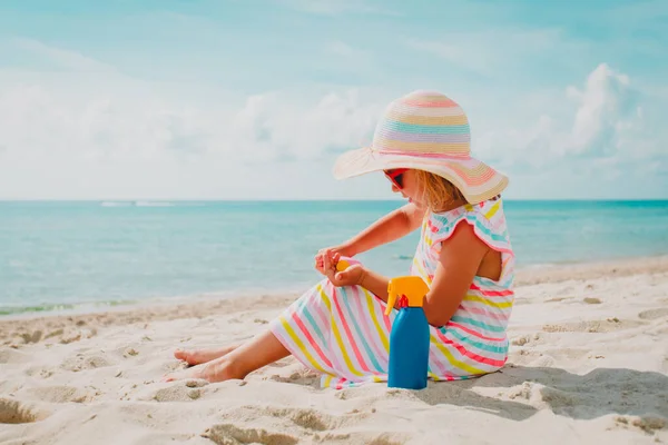 Маленькая девочка с солнцезащитным кремом на пляже отдыха, защита от солнца — стоковое фото