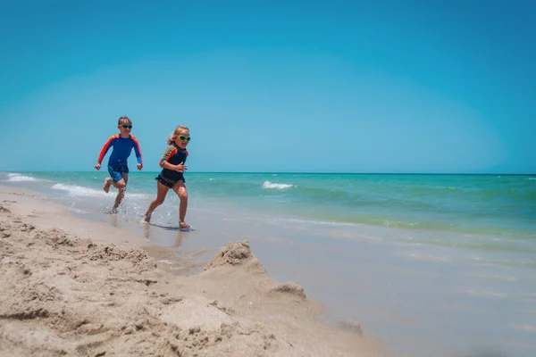 Děti běží, chlapec a dívka bavte se na tropické pláži — Stock fotografie