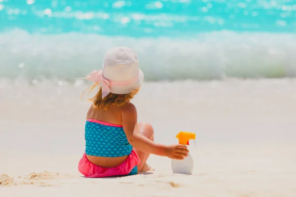 Holčička s krémem na opalování na tropické pláži — Stock fotografie