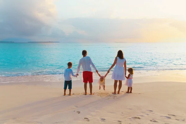 Çocuklu mutlu bir aile gün batımı kumsalında oynuyor. — Stok fotoğraf