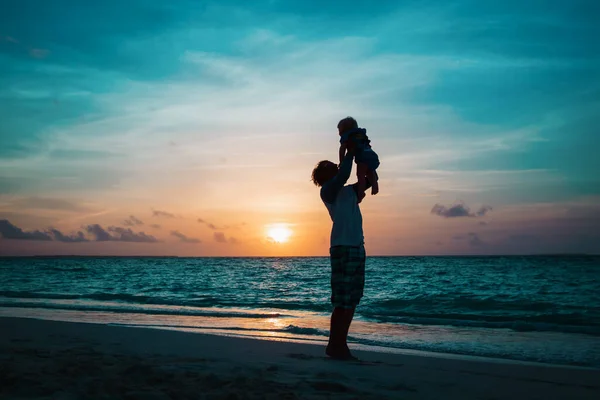 Vader en dochter silhouetten op het strand bij zonsondergang — Stockfoto