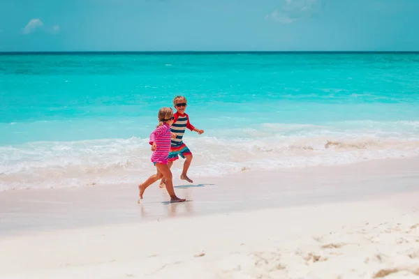 Menino feliz e menina correndo na praia — Fotografia de Stock